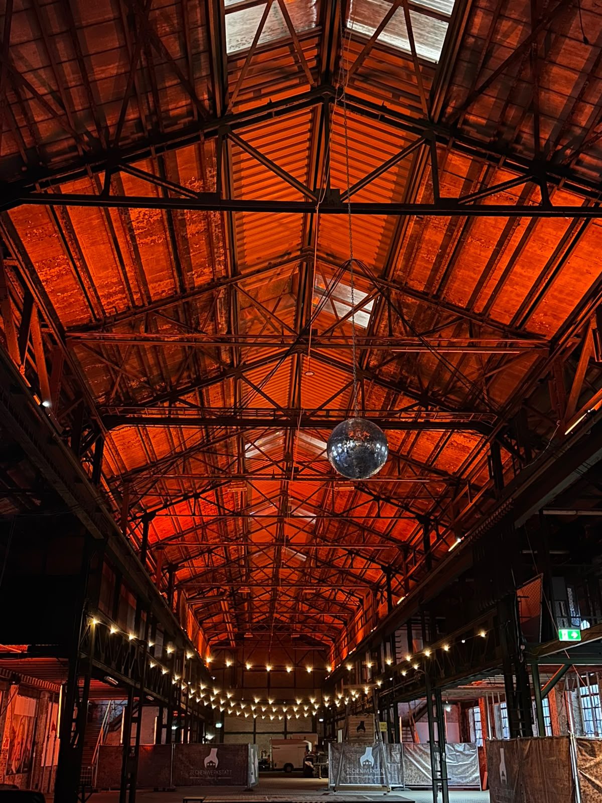 Die Stahlhalle der Zechenwerkstatt Lohberg in warmem Licht, mit Discokugel und Lichterketten
